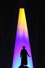 Statue of a soldier in front of Bunker Hill Monument illuminated purple and gold at night