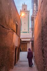 narrow street in Marrakech old medina with a woman in traditional Moroccan clothing