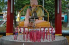 lone joss stick in front of Buddha statue