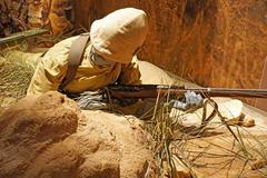 Royal Canadian Regiment soldier partially behind a large ant-hill during the South African War