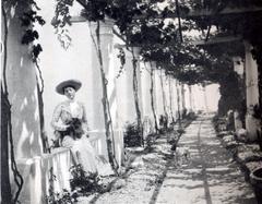 Princess Marie Louise of Hanover with two dogs under a pergola in Capri