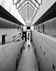 Two women walking and talking in a long corridor at the National Gallery of Canada with natural light from skylights.