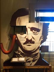 Museum exhibit with a book and large cutout of Edgar Allan Poe's head