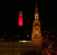 Coit Tower glowing red behind Saints Peter and Paul Church