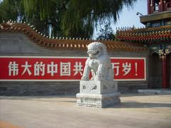 Stone lions in front of Xinhuamen gate with a slogan displaying 'Long live the great Communist Party of China'