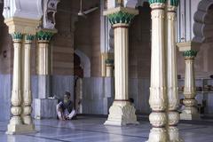 Man sitting between columns of a mosque in Delhi, India