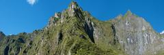 Steep cliffs surrounding Machu Picchu with Urubamba river and train tracks in view