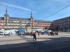 Madrid's Plaza Mayor on a sunny day with people walking and sitting outdoors