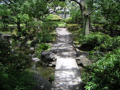 Scenic view of Kyu-Yasuda Garden in Tokyo with a pond, trees, and surrounding buildings