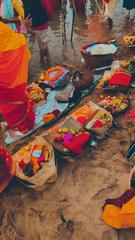 People worshipping at ghats during sunrise with fruits and thekua