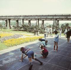 Children drawing on asphalt near a pergola in a historical garden in Wroclaw