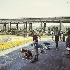 children drawing on asphalt near a pergola in historic gardens of Wroclaw