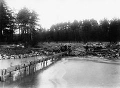 Black and white image of Alppipuiston pond with railway embankment restoration work