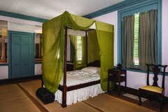 Room with four-post bed and green drapery, trunk, and washbasin