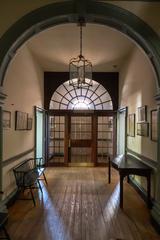 view of a central hall looking toward the main door with a bench and table with prints above lining the hallway