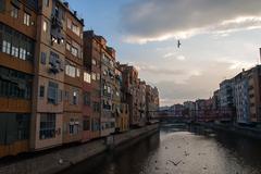 Colorful houses along the Onyar River in Girona, Spain with an iron bridge in view