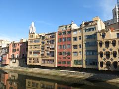 Façana del riu in Girona with colorful buildings along the Onyar River and Sant Feliu church in the background