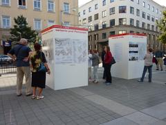 People viewing informational pillars in Moravské Square, Brno, about the 2016 local referendum on the main railway station location