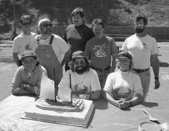 group of people with a large cake on a table