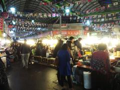 inside of Gwangjang Market with food stalls, vendors, and customers