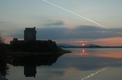 Dunguaire Castle reflecting in calm water during sunset