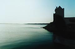 Dunguaire Castle by the water under a cloudy sky