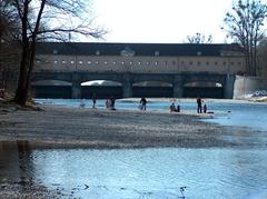 northern side of Oberföhring dam in landscape conservation area Hirschau and Obere Isarau with a group of people, some with bicycles, on the gravel bank