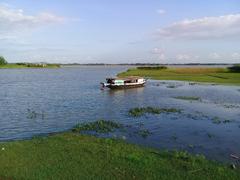 Scenic view of a large lake surrounded by trees and a distant hill under a clear sky in Hajipur, Bijoynagar Upazila, Bangladesh