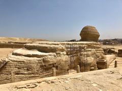 The Great Sphinx of Giza with partially buried lower portion and Pyramids of Giza in the background