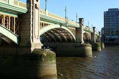 Southwark Bridge in London spanning the River Thames with city buildings in the background