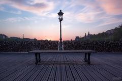 Couple sharing a moment on Pont des Arts bridge in Paris during sunset