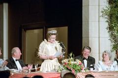 President Ronald Reagan laughing at dinner in honor of Queen Elizabeth II with George Shultz and Helena Shultz