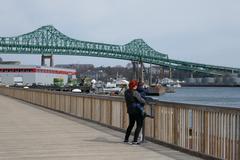 woman and child walking along Boston Harborwalk with Tobin Bridge in background