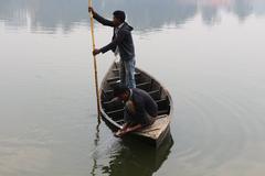 Bangladeshi fisherman fishing in early morning by a small wooden boat