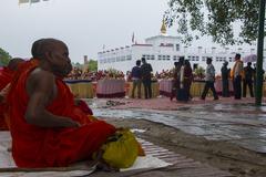 Buddha Jayanti celebration with people lighting candles in front of a large Buddha statue