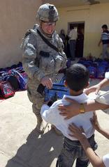 Spc. James Robert handing a backpack to an Iraqi boy