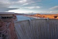 Aerial view of a large dam holding back the waters of Lake Powell with arid mountains in the background near Page, Arizona