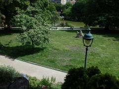 Panoramic view of Parc Montsouris in Paris with lush greenery, a serene pond, and people enjoying the scenery