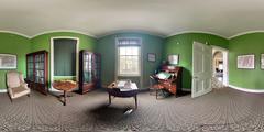 360 image of a desk, chairs, tea tables, a winged armchair, and bookcases with lime green walls