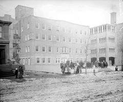 Children standing in a line on a retaining wall on the grounds of Hull House