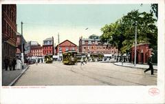 Harvard Square bustling with people and traffic on a sunny day