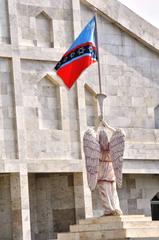 Angel blowing trumpet with Holy Church flag in background