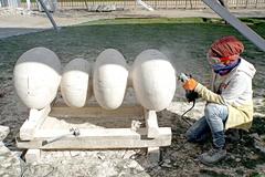 sculptor working on a large marble sculpture outdoors at the Parque de las Esculturas