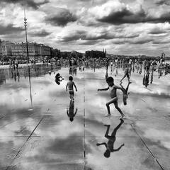 Children playing in the water at the Water Mirror in Place de la Bourse, Bordeaux, France