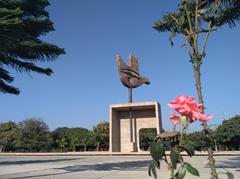 Close-up of a red rose with the Open Hand Monument in the background in Chandigarh, India