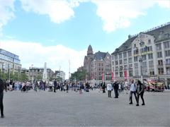 Dam Square, Amsterdam, with people gathering on a sunny day