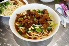 bowl of noodles with marinated beef and vegetables