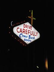 a view of the road leaving Las Vegas with a car driving away and city lights visible in the background