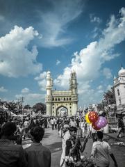 The Charminar in Hyderabad amidst bustling streets with colorful balloons and clouds enhancing its beauty