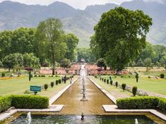 A beautiful view of Nishat Bagh, a terraced Mughal garden with lush greenery and a stunning mountain backdrop